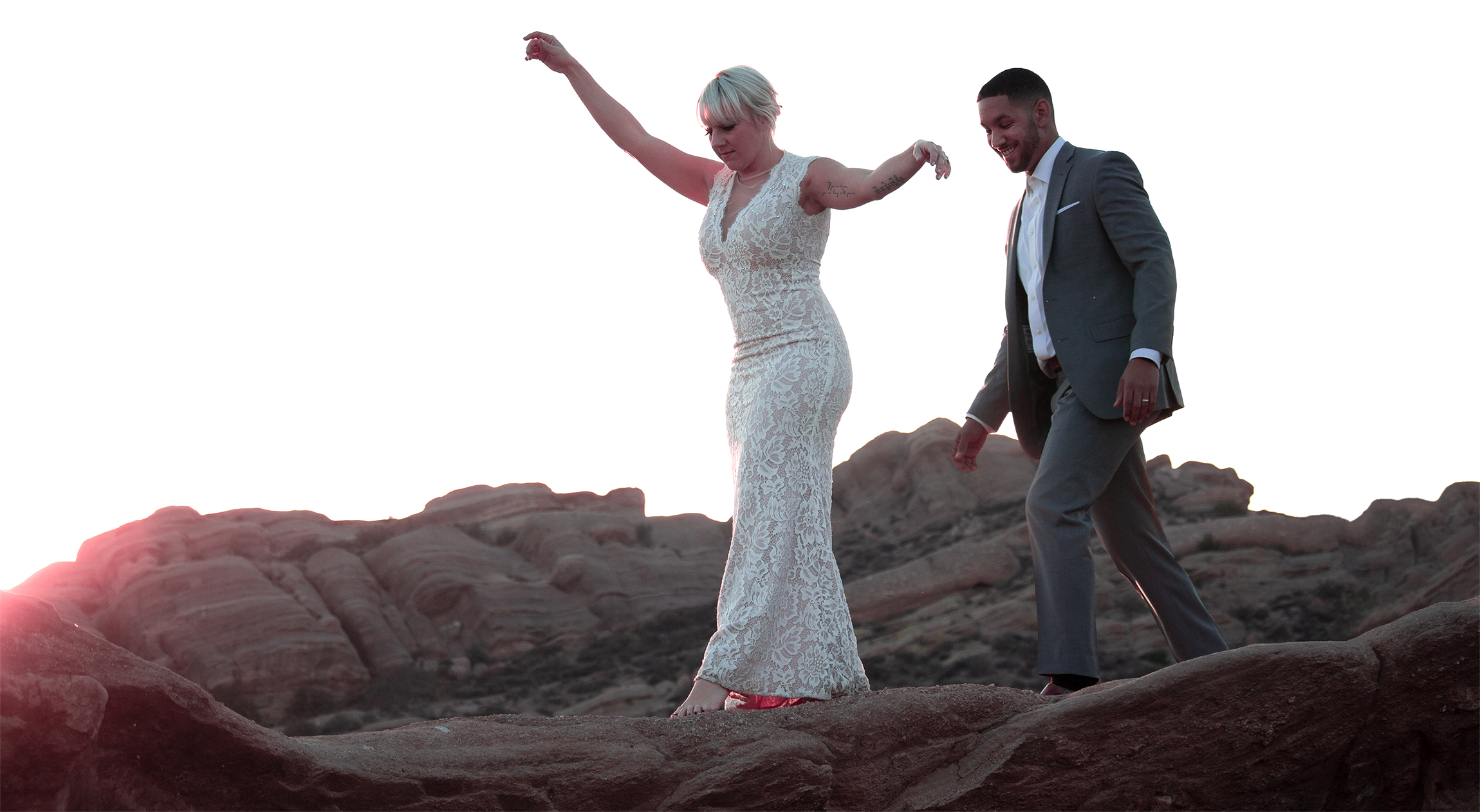 Bride and groom walking along a rocky ridge.
